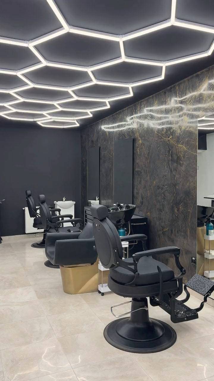 Salonul ROOT: tavanul cu lumini hexagonale, peretele de marmură neagră cu vene aurii și scaunele de lucru